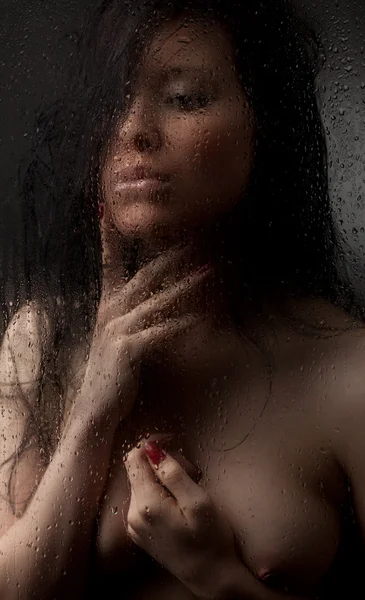 stock image Naked girl in a wet glass on a black background