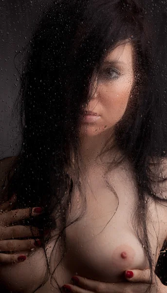 stock image Naked girl in a wet glass on a black background