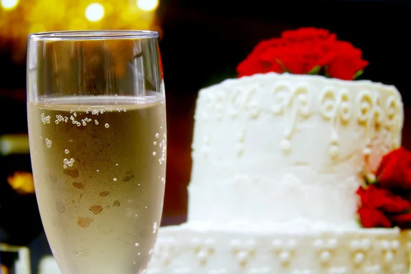 Ποτήρι σαμπάνια και γαμήλια τούρτα με λουλούδια — Φωτογραφία Αρχείου